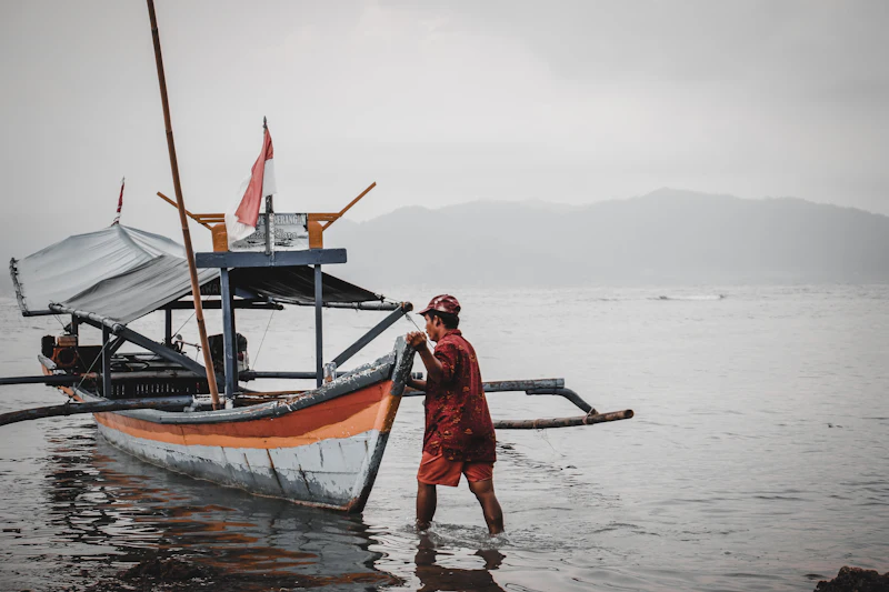Nelayan menarik perahu cadik tradisional di tepi laut